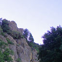 tree studded rock face rising to left of gravel road