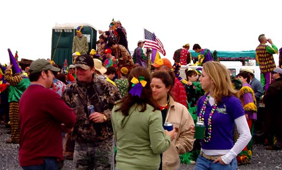 a crowd of people minging and talking, wearing colorful Mardi Gras clothes